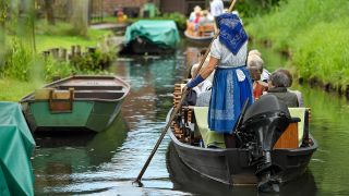 Eine Kahnfährfrau trägt eine sorbisch-wendische Arbeitstracht und fährt Touristen in einem Kahn über ein Fließ, so werden die Wasserwege im Spreewald genannt. (Quelle: dpa/Patrick Pleul)