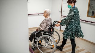 Symbolbild: Eine Pflegerin begleitet eine Seniorin im Rollstuhl. (Quelle: dpa/M. Kusch)