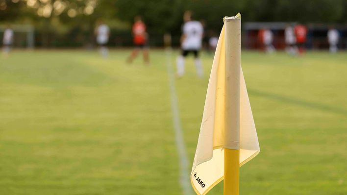 Eine Eckfahne beim Fußball, im Hintergrund läuft ein Spiel. Quelle: imago images/Claus Bergmann