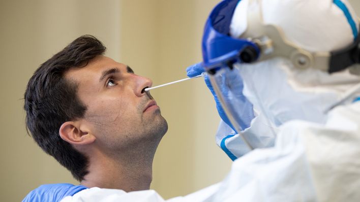 Ein Mitarbeiter des Gesundheitsamts der Stadt Köln demonstriert bei einem Mann einen Corona-Test per Nasenabstrich. (Quelle: dpa/Marius Becker)