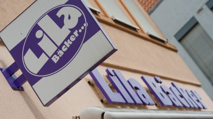 An einem Geschäft hängt das Firmen-Schild mit dem Logo der Bäckereikette Lila Bäcker (Quelle: DPA/Stefan Sauer)