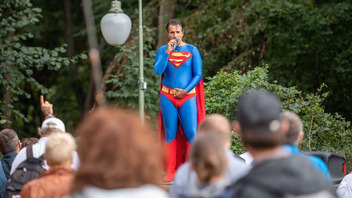 Ein Kundgebungsteilnehmer in Superman-Kostüm spricht bei einer Demonstration gegen die Corona-Maßnahmen am 1.9.2020 an der Siegessäule (Quelle: DPA/Christophe Gateau)