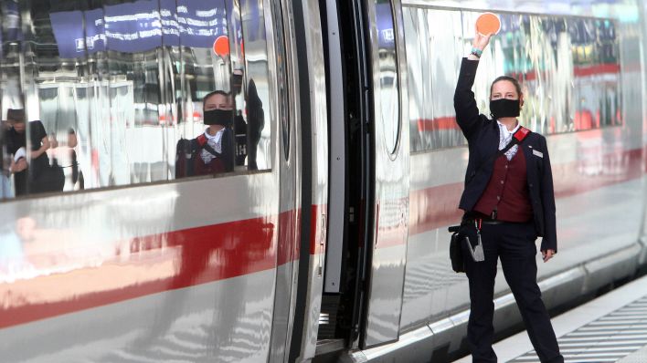 Eine Zugbegleiterin der Deutschen Bahn trägt während der Zugabfertigung im Bahnhof eine Mund-Nase-Bedeckung (Bild: imago images/Ralph Peters)