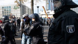 Ein Polizist hindert am 25.10.2020 einen Teilnehmer der Demonstration gegen die Corona-Auflagen auf dem Alexanderplatz am Weitergehen. (Quelle: dpa/Paul Zinken)