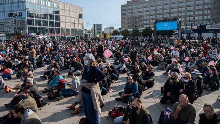 Teilnehmer an Demonstration gegen die Corona-Auflagen sitzen am 25.10.2020 am Alexanderplatz auf dem Boden. (Quelle: dpa/Paul Zinken)