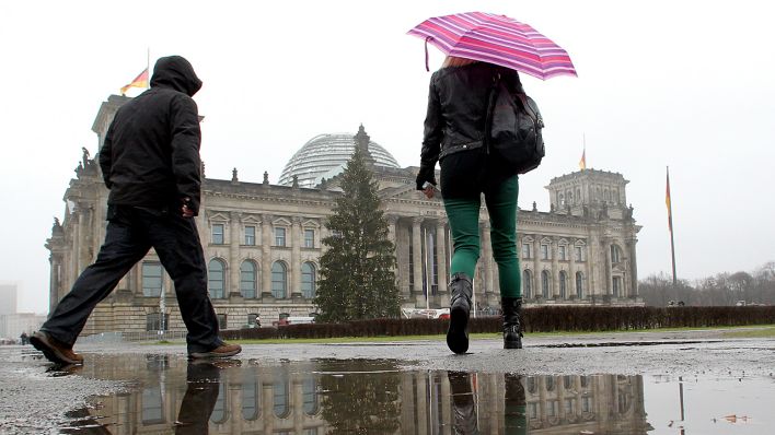 Symbolbild: Menschen laufen im Regen am 10. Dezember 2013 am Reichstag vorbei. (Quelle: dpa/Wolfgang Kumm)