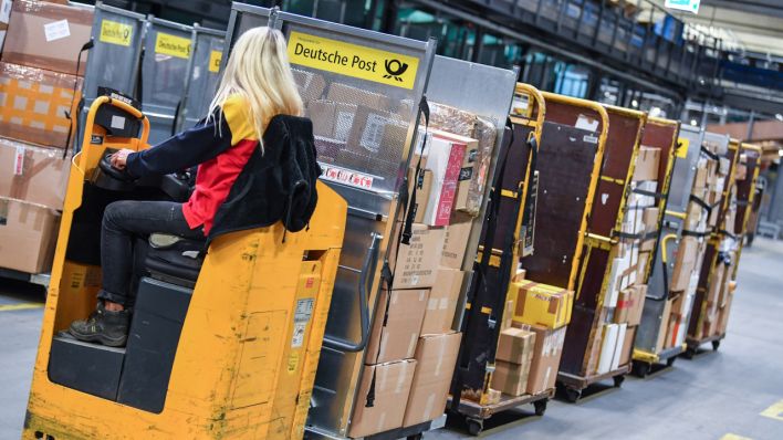 Eine Frau fährt Pakete durch das DHL-Paketzentrum in Rüdersdorf, Archivbild (Quelle: DPA/Patrick Pleul)
