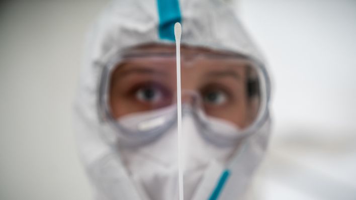 Eine Mitarbeiterin des medizinischen Personals betrachtet ein Wattestäbchen nach einem PCR-Abstrich zum Test auf Covid-19 (Quelle: DPA/Michael Kappeler)