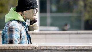 Ein Mann trägt eine Gasmaske um sich vor dem Coronvirus zu schützen. (Quelle: dpa/Martin Baumann)