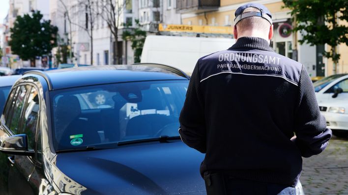 Ein Mitarbeiter vom Ordnungsamt Berlin kontrolliert ein Auto in der Samariterstraße. Foto: Annette Riedl/dpa
