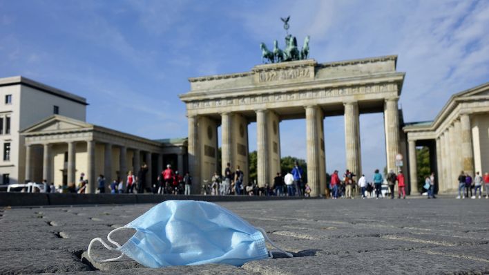 Symbolbild: Eine Mundschutzmaske liegt auf dem Pariser Platz vor dem Brandenburger Tor auf dem Boden. (Quelle: dpa/S. Steinach)