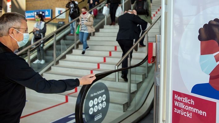 Brandenburg, Potsdam: Passanten mit Mundschutz gehen im Hauptbahnhof an einem Schild der Bahnhofs-Passagen mit der Aufschrift «Herzlich willkommen zurück! Tragepflicht Mund-Nasen-Bedeckung.» vorbei. (Quelle: dpa/Stache)