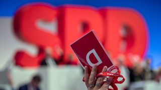 Ein Delegierter hält bei einem SPD-Parteitag seine Stimmkarte hoch (Quelle: dpa/Michael Kappeler)