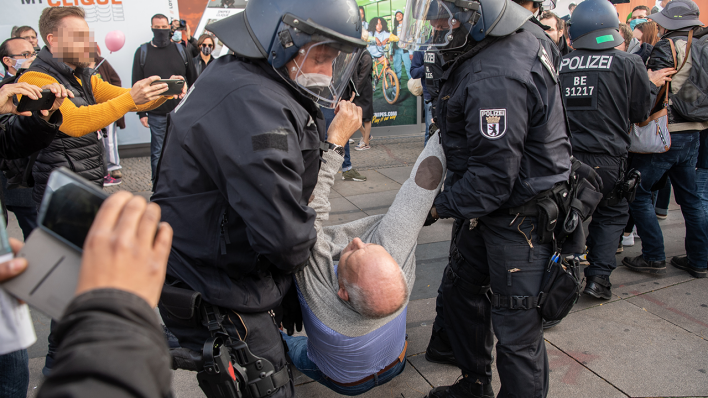 Polizisten tragen einen Teilnehmer der Demonstration gegen die Corona-Auflagen auf dem Alexanderplatz weg (Quelle: dpa/Paul Zinken)
