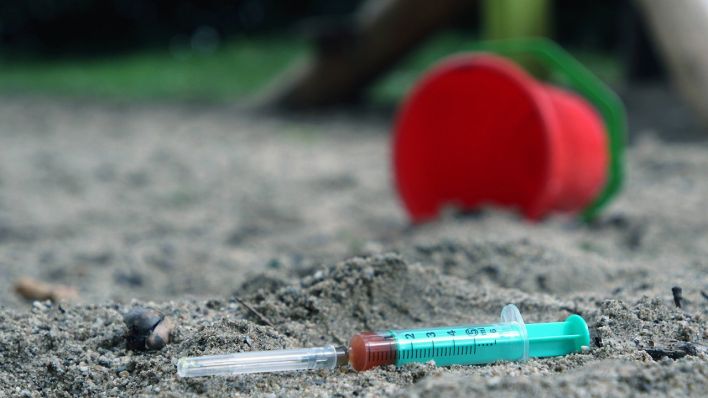 Die Einwegspritze einer drogenabhängigen Person liegt zurückgelassen auf einem Kinderspielplatz. Quelle: www.imago-images.de