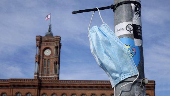 Symbolbild - Ein Einweg-Mund-Nasen-Schutz hängt am 03.10.2020 an einem Pfeiler vor dem Roten Rathaus in Berlin. (Bild: imago images/Sascha Steinach)