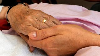 Archivbild: Eine Pflegerin hält am 03.06.2009 die Hand einer todkranken Patientin. (Quelle: dpa/Norbert Försterling)