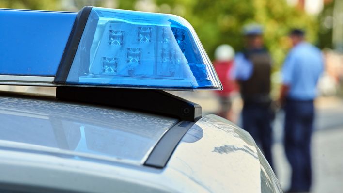 Symbolbild - Hinter der Lichtanlage eines Polizeiautos stehen Polizisten. (Bild: dpa/Annette Riedl)