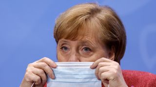 Bundeskanzlerin Angela Merkel (CDU) setzt sich ihre Mund-Nasen-Bedeckung auf, bevor sie nach einer Pressekonferenz einen Saal im Bundeskanzleramt verlässt