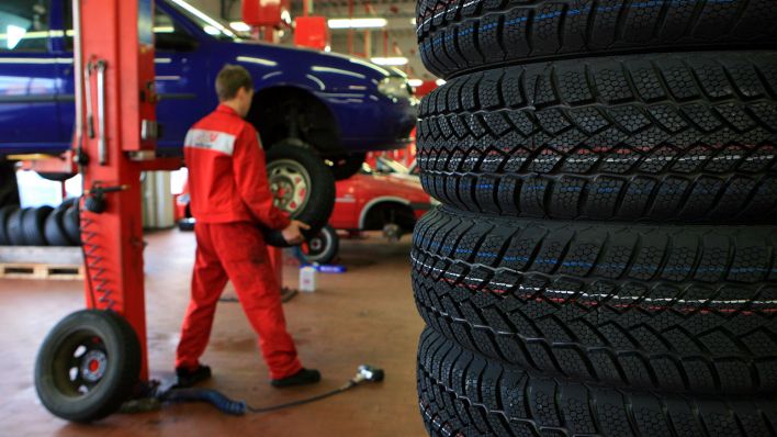 Symbolbild - Ein Mitarbeiter wechselt in einer Autowerkstatt einen Reifen. (Bild: dpa/Patrick Pleul)