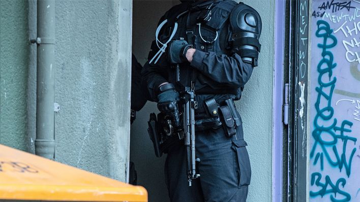 Symbolbild: 17.11.2020, Berlin: Eine bewaffnete Polizeibeamter steht an einem Wohnhaus an der Gitschiner Straße (Bild: dpa/Paul Zinken)