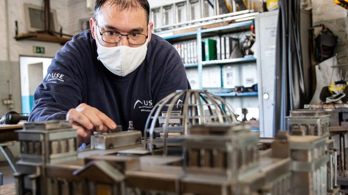 Ein Mann arbeitet in der Metallwerkstatt der Union Sozialer Einrichtungen (USE) an einem Modell des Reichstages (Bild: dpa/Lennart Stock)