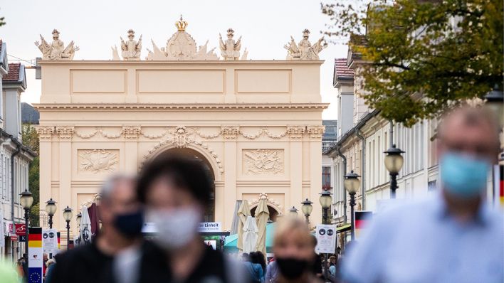 Symbolbild: Passanten mit Masken gehen vor dem Potsdamer Brandenburger Tor. In großen Teilen der Potsdamer Innenstadt gilt Maskenpflicht. (Quelle: dpa/C. Soeder)