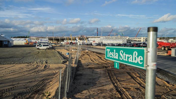ARCHIV - 05.11.2020, Brandenburg, Grünheide: Blick auf das Straßenschild «Tesla Straße 1» vor der Baustelle der Tesla-Fabrik. (Quelle: dpa/Jörg Carstensen)