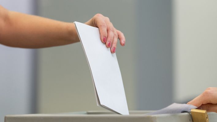 Eine Wählerin wirft bei der Stimmabgabe in einem Wahllokal einen Stimmzettel in eine Wahlurne. Foto: Robert Michael/dpa