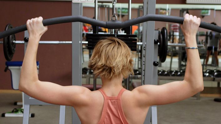 Eine Frau trainiert im Fitnesstudio ihre Rückenmuskulatur (Quelle: imago/Shotshop).