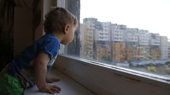 Ein Kind blickt 2020 in Berlin aus dem Fenster. (Quelle: Dominik Wurnig)