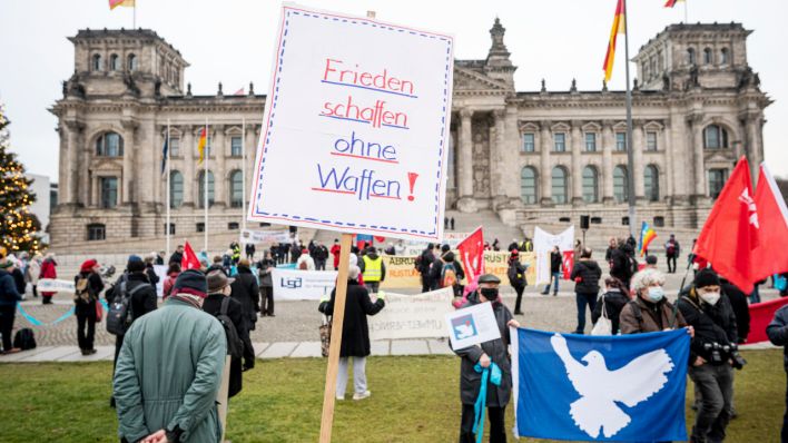 Ein Teilnehmer steht beim bundesweiten Aktionstag "Abrüsten statt Aufrüsten" mit einem Schild mit der Aufschrift "Frieden Schaffen ohne Waffen!" vor dem Bundestag. (Quelle: dpa/Fabian Sommer)