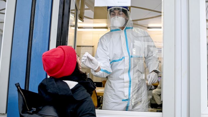 Ein Medizinischer Mitarbeiter führt am 11.12.2020 bei einer jungen Frau einen Rachenabstrich für einen SARS-CoV-2-Antigentest, im Corona-Antigen- Schnelltestzentrum am Mauerpark im Berliner Bezirk Prenzlauer Berg, durch. (Quelle: dpa/Britta Pedersen)