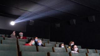 Symbolbild: Mehrere Menschen sitzen mit Masken in einem Schweizer Kino (Bild: dpa/Gaetan Bally)