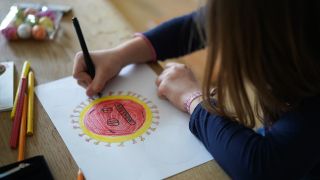 Symbolbild: Ein Kita-Kind malt ein Coronavirus