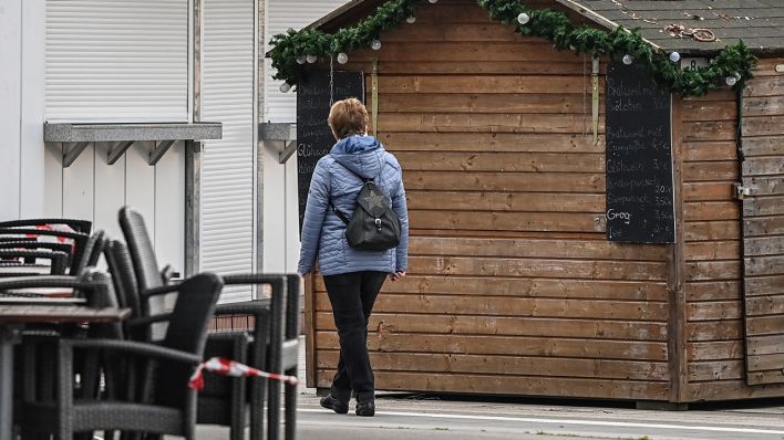 Eine Frau läuft an der Promenade am Senftenberger See vor geschlossenen Weihnachtshütten (Bild: dpa/Patrick Pleul)