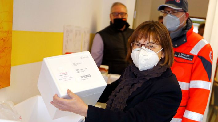 Ursula Nonnemacher, Gesundheitsministerin in Brandenburg, hält eine Kiste mit Impfstoffdosen in den Händen (Quelle: Reuters/Fabrizio Bensch)