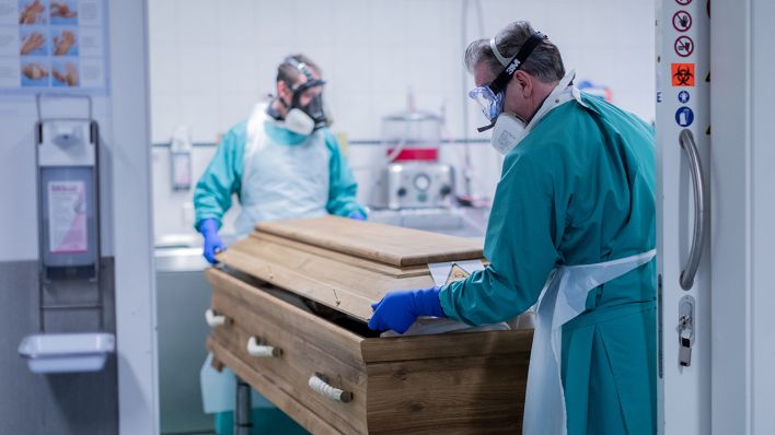 Symbolbild: Ein Bestattungsunternehmer und sein Mitarbeiter schließen einen Sarg mit einem Verstorbenen, der an oder mit dem Coronavirus gestorben ist. (Quelle: dpa/R. Vennenbernd)