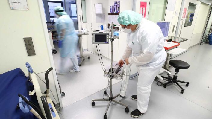 Pflegekräfte verbringen medizinisches Gerät in ein Krankenzimmer auf einer Covid-19-Intensivstation (Quelle: dpa-Zentralbild/Bodo Schackow)