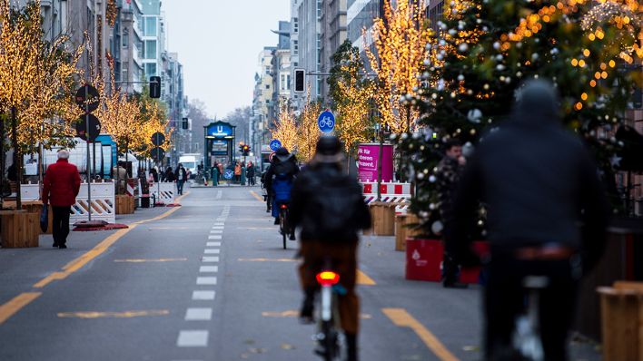 Auf der weihnachtlich geschmückten Friedrichstraße fahren Radfahrer. (Quelle: dpa/Kira Hofmann)