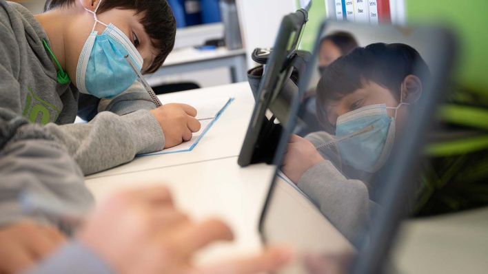 Ein Schüler mit Mundschutz spiegelt sich auf einem Tablet (Quelle: dpa/Sebastian Gollnow)