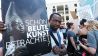 "Heute schon Beutekunst betrachtet?" ist auf dem Schild zu lesen, das ein Demonstrant am 12.06.2015 in Berlin beim Richtfest des Berliner Stadtschlosses - Humboldtforum hält. (Quelle: dpa/Stephanie Pilick)