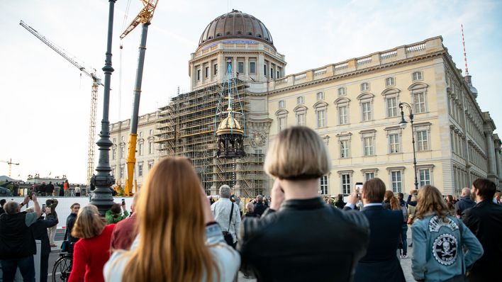 Ein Kran hebt am Neubau vom Berliner Schloss, dem Humboldt Forum, die Kuppelspitze mit Engelsfiguren und einem Kreuz auf die Kuppel. (Quelle: dpa/Bernd von Jutrczenka)