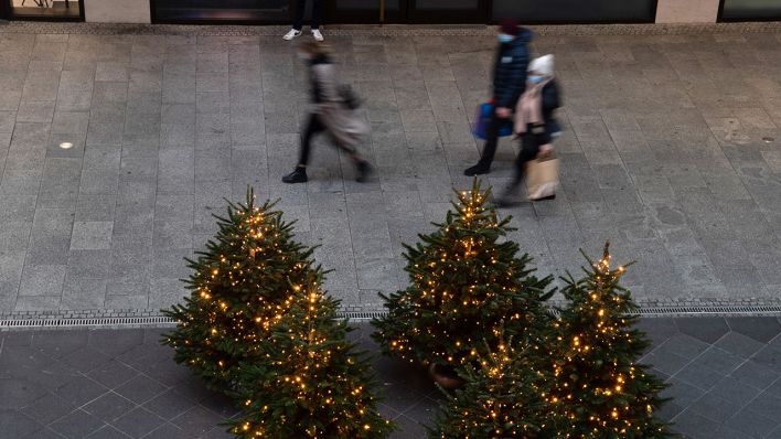 Nur wenige Menschen gehen an weihnachtlich geschmückten Tannenbäumen in einem Einkaufszentrum vorbei. Vielerorts hielt sich der Ansturm auf die Geschäfte in Maßen. Quelle: dpa/Paul Zinken