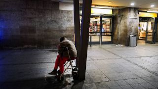Ein Obdachloser sitzt vor dem Eingang zum Bahnhof Zoo in Berlin (Quelle: imago images/Jürgen Ritter)