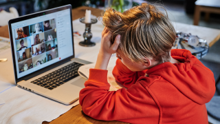Symbolbild: Ein Grundschüler sitzt zuhause vor dem Bildschirm und nimmt mit einem Laptop am Onlineunterricht mit dem Lehrer teil