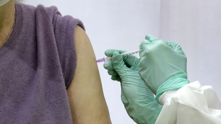 Eine Frau erhält eine Corona-Impfung in ihren Oberarm