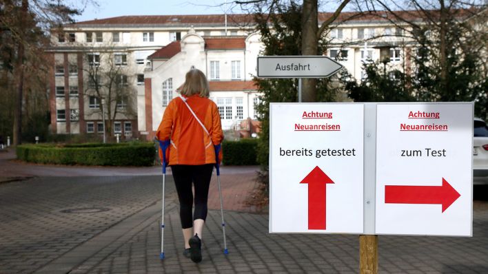 Eine Frau geht an einem Wegweiser vor der Median Klinik in Hoppegarten nahe Berlin vorbei. In dem Rehabilitationszentrum soll es zu einem massiven Corona-Ausbruch gekommen sein. (Quelle: dpa/Wolfgang Kumm)