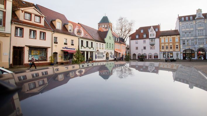Symbolbild: Häuser am relativ leeren Marktplatz von Senftenberg im südbrandenburgischen Landkreis Oberspreewald-Lausitz spiegeln sich in einem Autodach. (Quelle: dpa/C. Soeder)