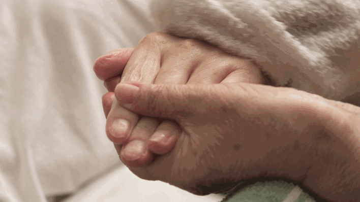 Häusliche Pflege: Eine Angehörige hält die Hand eines Demenzkranken (Bild: imago images/Martin Wagner)